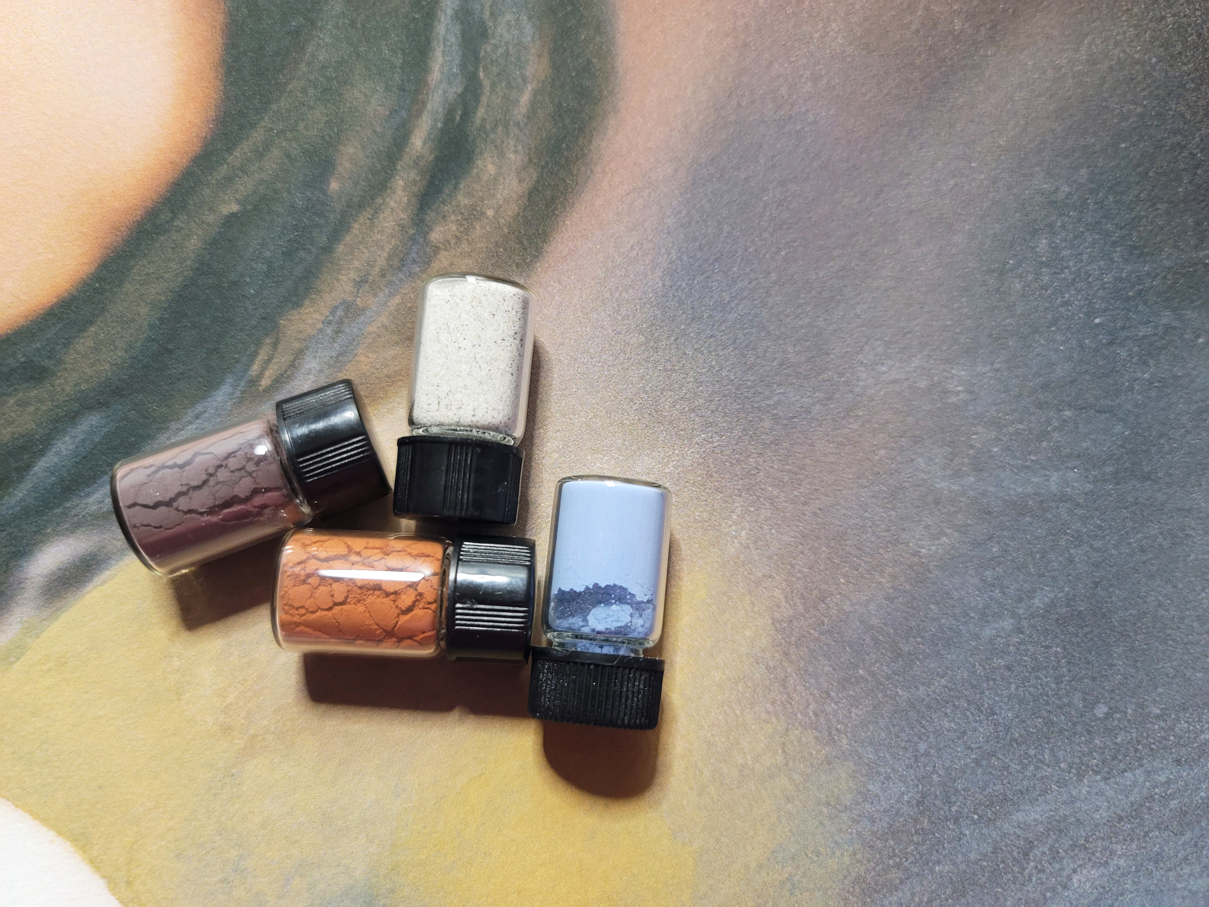 Four bottles of handmade pigment made by Jordan A. Cook for The Kiss, shown in close-up.